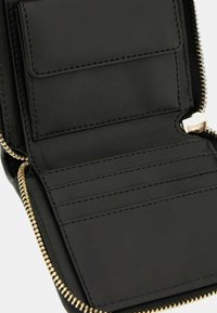 Intérieur d'un portefeuille en cuir noir avec fermeture à glissière, emplacements pour cartes et une poche ouverte. Caractéristiques : couture soignée et quincaillerie à fermeture éclair dorée.