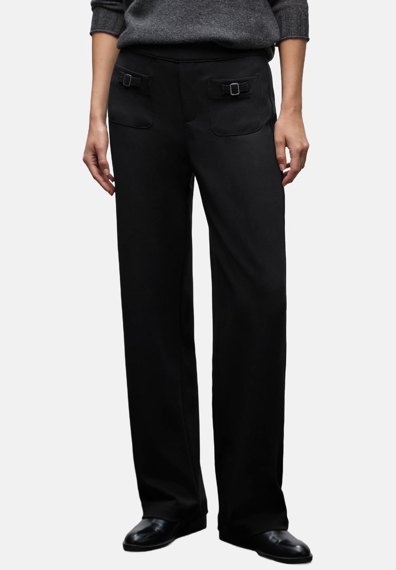 Pantaloni neri a gamba larga realizzati in tessuto liscio, con due tasche frontali decorate da fibbie e una cintura elastica.