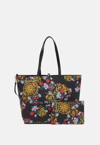 Černá taška přes rameno s květinovými a zlatými barokními vzory, vybavená dvěma dlouhými uchy a menší odpovídající kapsou. Hladká textilie.