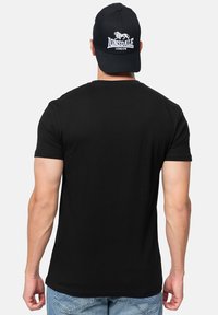 Sort bomulds t-shirt med korte ærmer og klassisk rund halsudskæring, kombineret med en sort cap med et hvidt broderet logo.