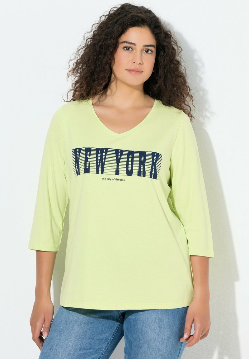 Jasnozielony t-shirt z dekoltem w serek i rękawami do łokcia, z granatowym nadrukiem "NEW YORK" oraz napisem "the city of dreams". Casualowy design.