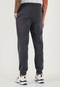 Tumed hallid dressipüksid, mis on valmistatud pehmest materjalist, elastse vöökoha, kitsenevatelaiendustega ja tagataskuga hoiustamiseks.