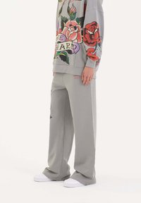 Grå sweatshirt och vida sweatpants har färgglada blommönster. Tyget är mjukt och passformen är avslappnad med ribbade mudd.