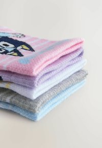 Fyra par strumpor staplade. Den översta strumpan är rosa med blå och svarta grafiska mönster; de övriga är ljuslila, vita och grå med subtila texturer.