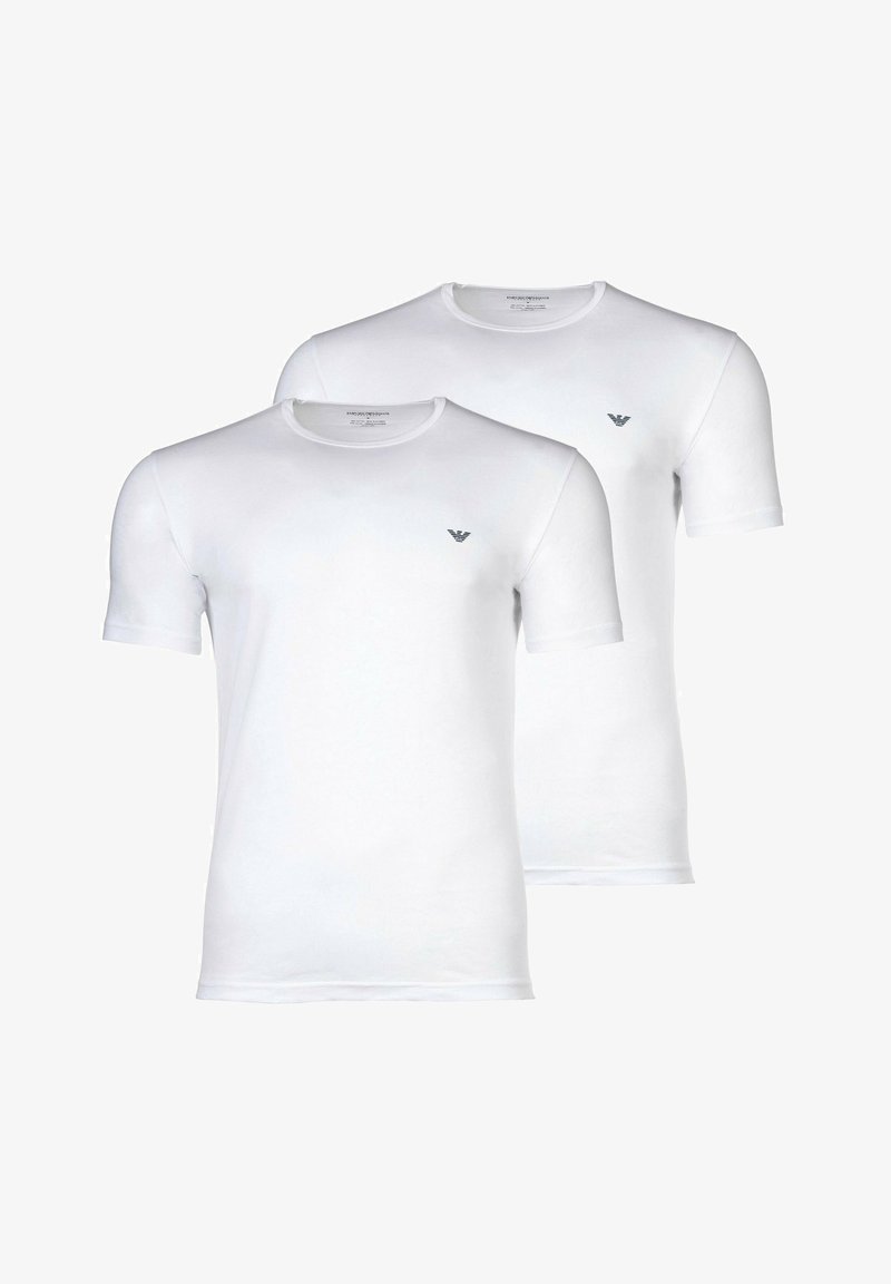 Twee eenvoudige witte T-shirts met korte mouwen en ronde halslijn, met een klein zwart logo op de linkerborst, weergegeven tegen een witte achtergrond.