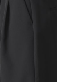 Czarna tkanina o gładkiej teksturze, z plisami i ukrytą boczną kieszenią, zaprojektowana dla dopasowanego kroju.