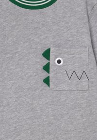 Felpa grigia con colletto a righe verdi e tasca con accenti triangolari verdi e dettagli ricamati di un occhio e una bocca.