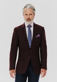 Burgundowy blazer o gładkiej fakturze, z klapami, dwoma przednimi kieszeniami i zapięciem na guziki; zestawiony z jasnoróżową koszulą i wzorzystym niebieskim krawatem.