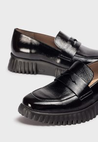 Zwarte gepatineerde leren loafers met een geraffineerde bovenkant, instapontwerp en een dikke ribbelzool. Heeft een subtiele decoratieve band.