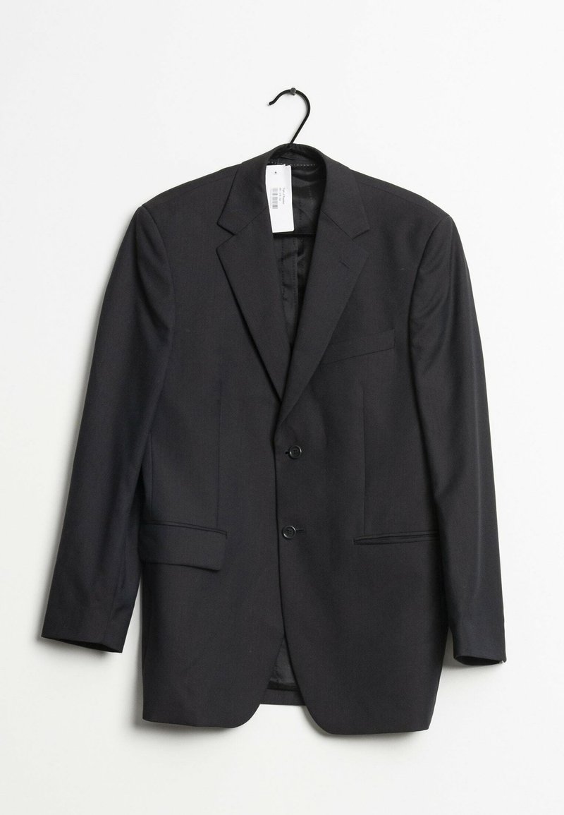 Veste noire en tissu texturé, dotée de deux boutons, de deux poches avant et de revers crantés. Accrochée à un crochet noir.