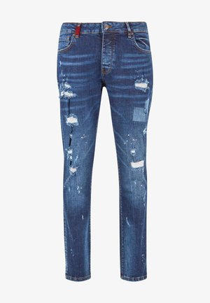 Jeans in denim blu con vestibilità slim, caratterizzati da toppe strappate, bordi sfilacciati e leggera scoloritura. Chiusura con bottone in metallo e zip.