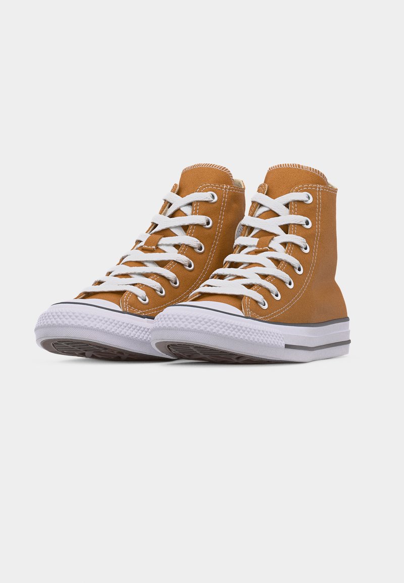 Zapatillas altas de lona color marrón claro con cordones blancos, ojales metálicos y suelas de goma blancas con una franja negra.