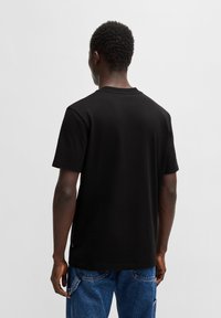 Svart bomullströja med rund hals, korta ärmar och en avslappnad passform. Tyget ser slätt ut, utan synliga mönster eller designer.