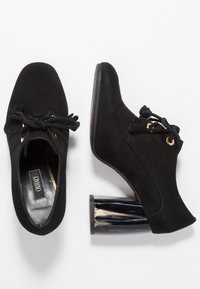 Svarta mocka ankle boots med rund tå, snörning i rep, gyllene ögla och en unik glänsande svart geometrisk klack. Slät textur genomgående.