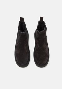 Botas de tobillo de ante negro con un acabado texturizado, paneles laterales elásticos y tiradores en la parte posterior para facilitar su uso. Interior forrado suave.