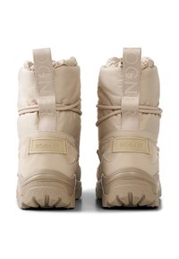 Beżowe zimowe buty z pikowaną cholewką, zaokrąglonym noskiem, sznurowaniem i gumową podeszwą. Na pięcie widoczne logo wykonane z metalu oraz materiałowe akcenty.