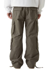 Spodnie cargo w oliwkowym kolorze z bawełny, z wieloma kieszeniami po bokach i z tyłu, regulowanymi sznurkami przy kostkach oraz luźnym krojem.