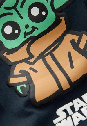 Tecknad karaktär med grön hud och stora svarta ögon, klädd i en brun kappa. Bakgrunden är mörkblå med vit "Star Wars" text.