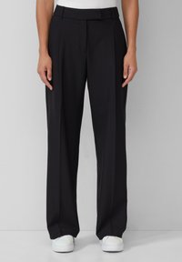 Pantalons noirs ajustés avec une coupe droite, présentant une texture lisse, des plis à l'avant et une taille épurée.