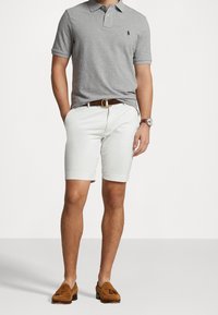 Šedé polo tričko, bílé šortky, hnědý kožený opasek, hnědé semišové mokasíny. D casualní outfit s texturovanou strukturou a pečlivým lemem.