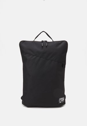 Schwarzer Rucksack aus Nylon mit rechteckiger Form, ausgestattet mit einem vorderen Reißverschluss, einem oberen Griff und einem Logotag in der unteren rechten Ecke.