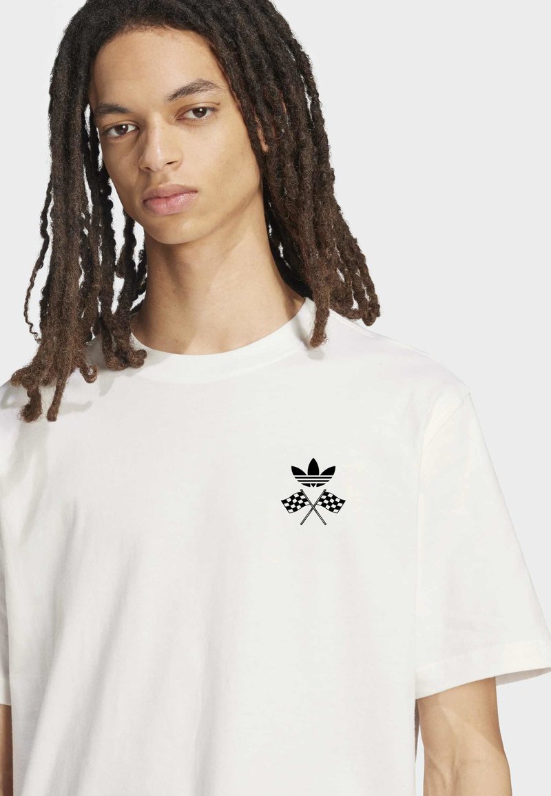 Vit kortärmad t-shirt av bomull med en svart grafik av en trebladig logotyp och korsade rutiga flaggor på bröstet.