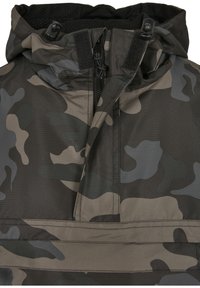 Fekete, szürke és zöld árnyalatú álcás pulóverdzseki. Magas gallérral, félig cipzárral és állítható kapucnival rendelkezik, amely húzózsinórral ellátott. Texturált anyag.