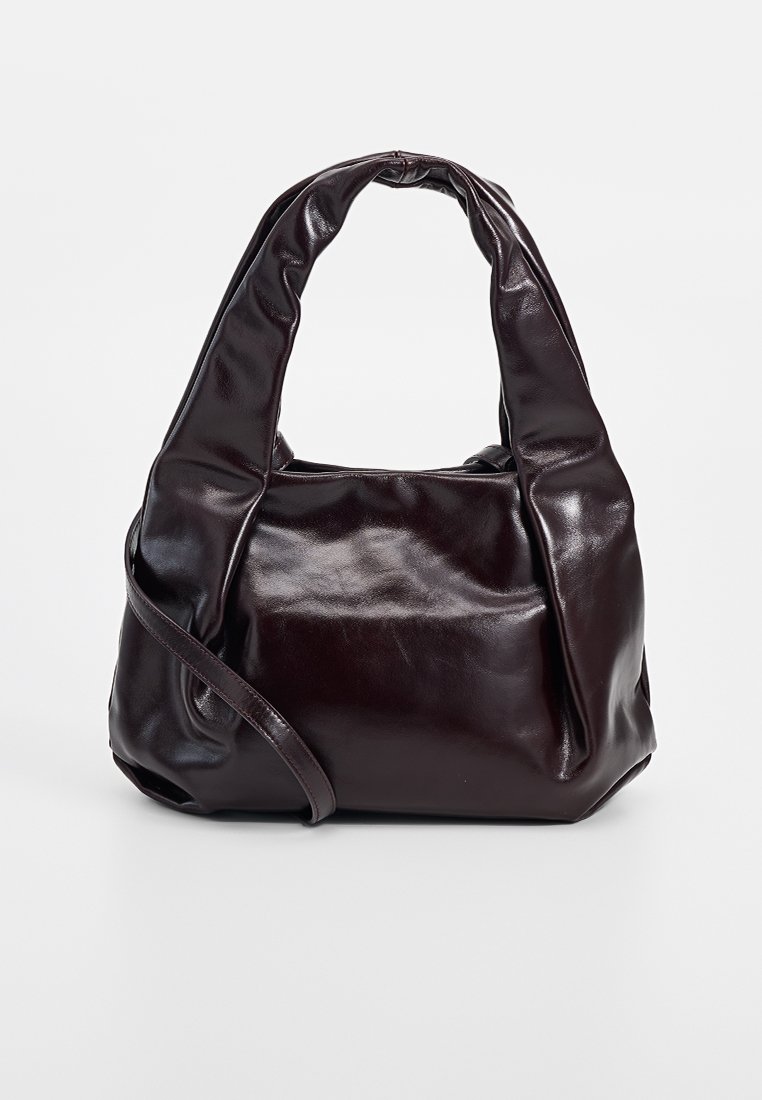 Sac à main en cuir marron foncé avec un design doux et structuré. Il possède des poignées incurvées et une seule bandoulière ajustable.