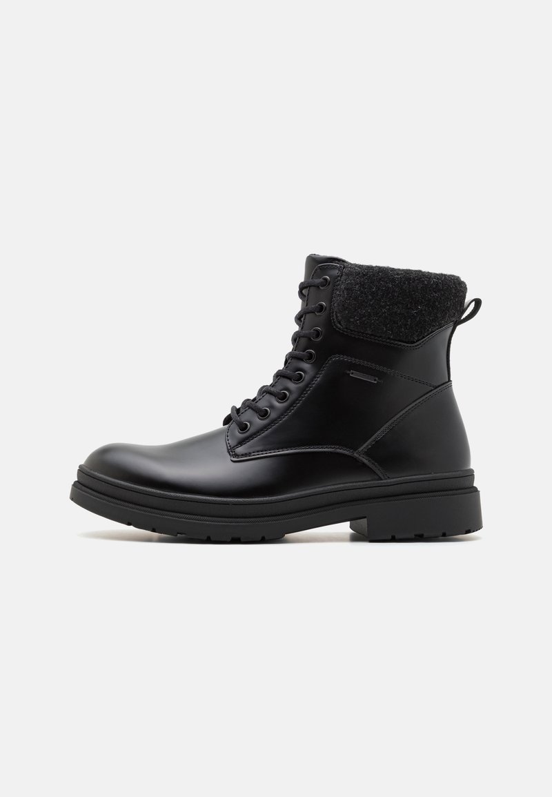 Bottine noire en cuir à lacets, avec col matelassé texturé et semelle épaisse en caoutchouc, vue de profil sur fond blanc.