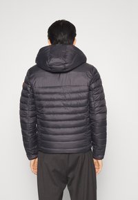 Giubbotto imbottito grigio scuro con cappuccio, caratterizzato da un design trapuntato, una texture liscia e polsini elasticizzati. Stile minimalista senza loghi visibili.