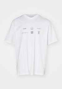 Camiseta blanca de algodón con un corte relajado, que presenta múltiples logotipos y gráficos plateados impresos en la parte frontal en diferentes estilos y tamaños.