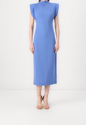 Femmes portant une robe bleue sans manches, longueur mollet, épaules structurées, et des talons beige à bride cheville, debout sur un fond blanc.