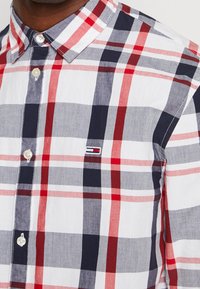 Lichte katoenen shirt met een geruite patroon in rood, marineblauw en grijs. Button-down kraag, korte mouwen en logo-detail op de borst.