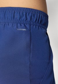 Tumesinised spordishortsid tekstuuriga viimistlusega. Elastselt vöökoht, millel on "CLIMACOOL" bränding. Küljeseam detail on nähtav.