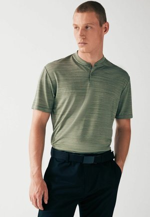 Polo de stil Henley, dintr-un material texturat de culoare verde măslinie, cu mâneci scurte, guler cu două butoane, asortat cu pantaloni negri cu talie.