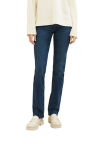Mørkeblå straight-leg jeans med medium vask, parret med kremfargede loafers. Stoffet har en myk tekstur og minimale sømdetaljer.