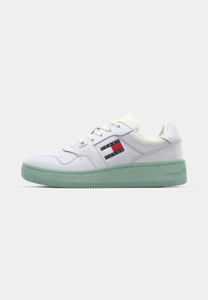 White sneaker made of smooth leather with a mint green rubber sole, featuring a branded fabric patch in red, white, and navy blue.