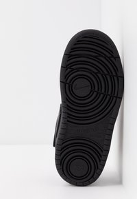 Svart gummisul med cirkulära mönster, med en Nike-logga och texten "ALL DAY PLAY". Sålarnas design är icke-veckande.