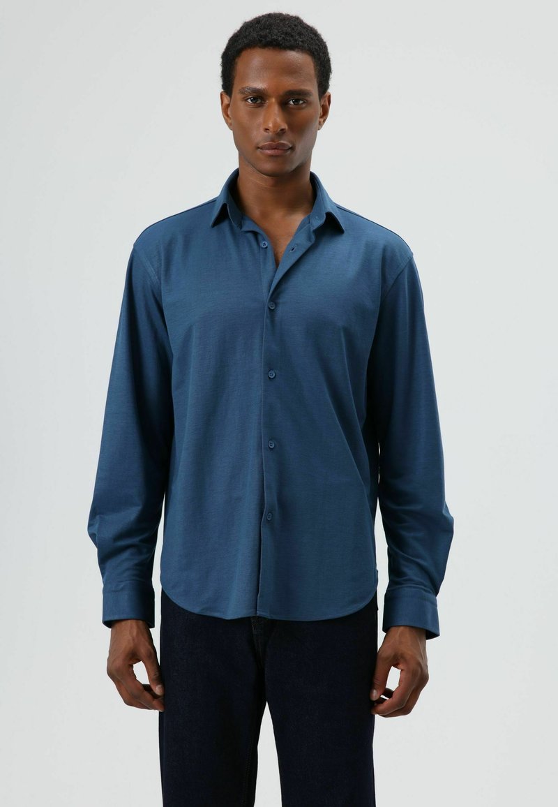 Overhemd met lange mouwen en knopen, gemaakt van een donker teal stof. Voorzien van een klassieke kraag en manchetten, met een gladde, zachte textuur en een getailleerde pasvorm.