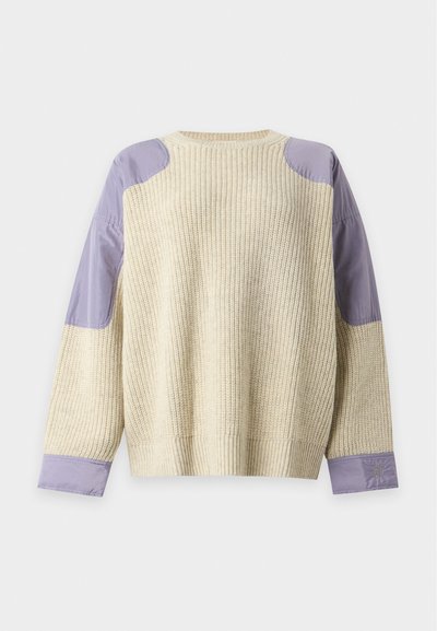 Pull en maille crème avec des patchs en tissu violet sur les épaules et les poignets, posé à plat sur fond blanc.