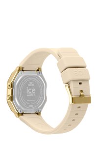 Montre en silicone beige clair avec un fond en acier inoxydable argenté octogonal et des accents dorés sur la boucle, présentant une texture lisse.