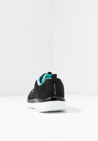 Svart och turkos Skechers-sneaker med vit sula, visad från baksidan på vit yta mot en plain vit bakgrund.