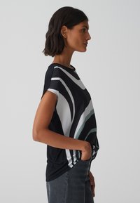 Zwart, kortemouwen top met gebogen witte en teal-strepen. Zachte textuur, relaxte pasvorm, met een ronde halslijn en zijzakken.