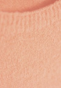 Brzoskwiniowy sweter, miękka tekstura, dziany wzór, ściągacz przy dekolcie, charakteryzujący się lekkim, puszystym wyglądem z delikatnym połyskiem.