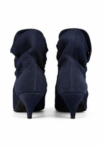 Bottines à talons hauts bleu marine avec une texture en suède doux, des détails froncés à l'arrière et un talon effilé.