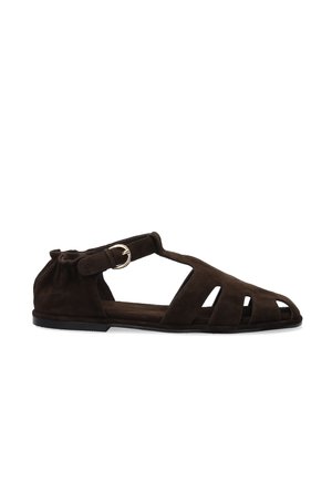 Dark brown suede flat sandal with cut-out design, ankle strap, and silver buckle on a white background.