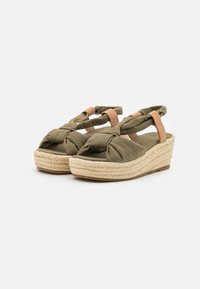 Olive green wedge sandals with knotted front design. Fabric straps with tan leather accents and braided jute sole. Textured footbed.