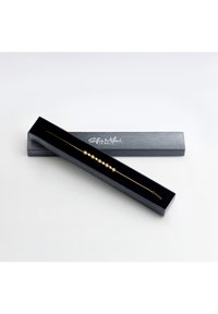 Goldarmband mit runden Perlenakzenten, präsentiert in einer schwarzen rechteckigen Box mit glatter Oberfläche undprägtem Logo auf dem Deckel.