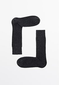 Grijze geribbelde sokken van zachte stof, ontworpen met een klassieke vorm en een textuurpatroon, voorzien van versterkte boordjes en tenen.