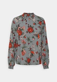 Blumenbluse mit hohem Hals, langen Ärmeln und elastischen Bündchen. Grauer Hintergrund mit bunten Mustern von Blumen und Schmetterlingen.
